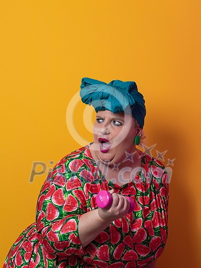 Fat woman dieting, fitness and health at home.Big woman and sport. Healthy, fitness and sports concept. Plus size young woman doing exercise with dumbbells on yellow background. High quality photo Fat woman dieting, fitness and health at home.Big woman and sport. Healthy, fitness and sports concept. Plus size young woman doing exercise with dumbbells on yellow background. High quality photo