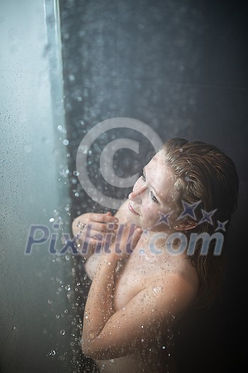 Pretty,young woman taking a long hot shower in a modern bathroom