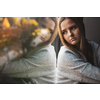 Depressed and anxious young woman sitting by a large window, feeling blue, sad, uncertain