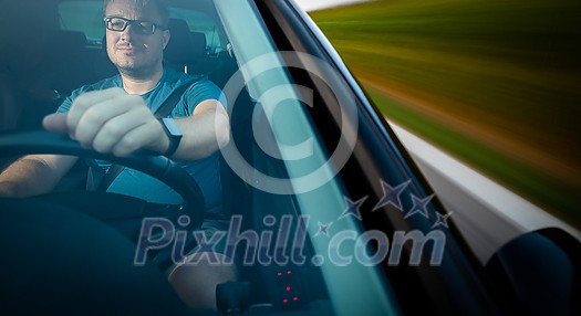 Handsome young driver driving hic car fast yet safely on the road (motion blurred image) Handsome young driver driving hic car fast yet safely on the road (motion blurred image)