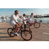 Happy family enjoying a beautiful morning by the sea together, parents riding a bike and their son riding an electric scooter. Selective focus. High-quality photo