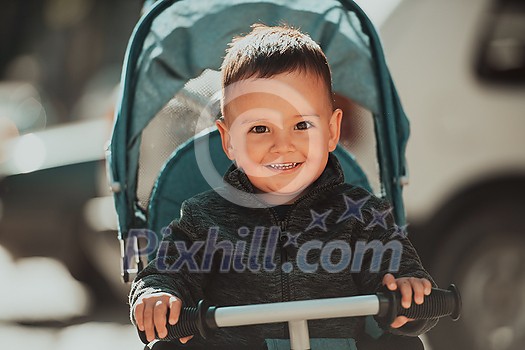 Sweet baby boy tow years old in a stroller bicycle outdoors. Little child in a pram. Infant kid in a pushchair. Spring walks with kids. High quality photo