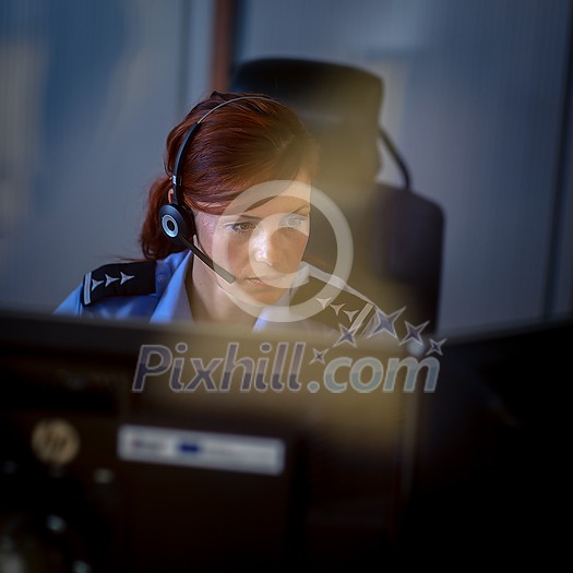Female police officer in a call center, listening carefully to an emergency call from a person in distress
