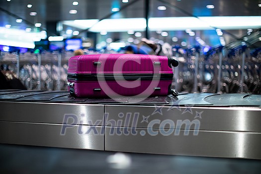 Arrived luggage going around on a conveyor belt waiting to be claimed at the baggage claim zone at a modern international airport