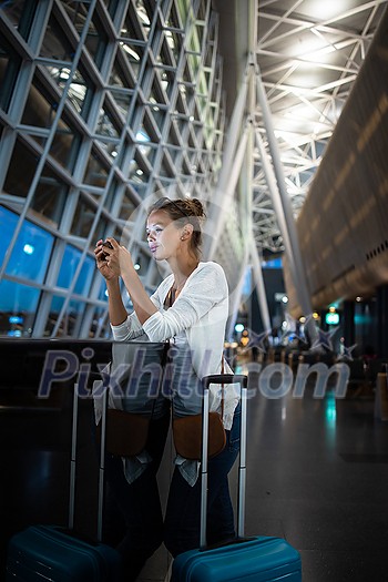 Young woman with her luggage at an international airport, waiting for her flight in the lounge zone after going through the  security check procedure