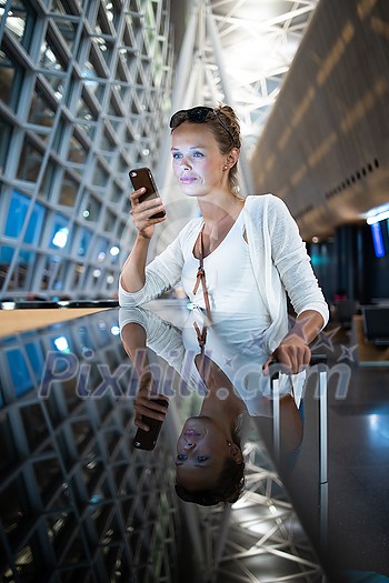 Young woman with her luggage at an international airport, waiting for her flight in the lounge zone after going through the  security check procedure