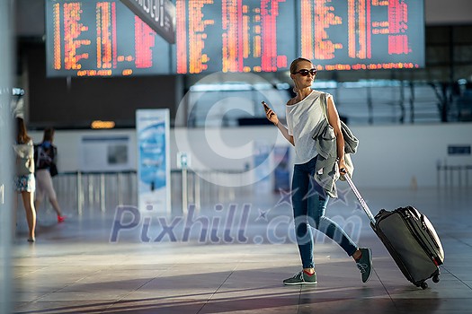 Young woman with her luggage at an international airport, before going through the check-in and the security check before her flight