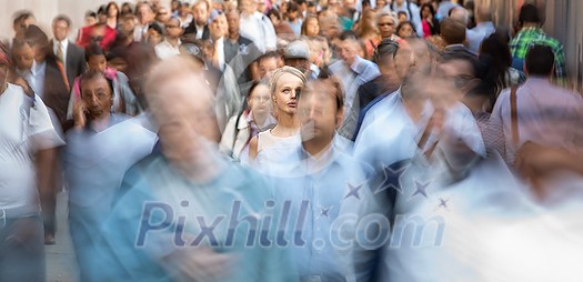 Crowd of people walking on city street - motion blurred image with unrecognizable faces - Young woman standing still, feeling down, depressed