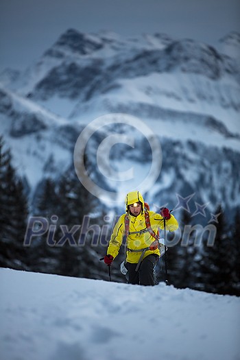 Young man snowshoeing in high mountains, enjoying splendid winter weather with abundance of snow