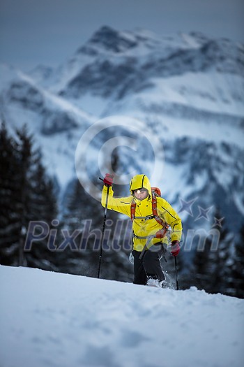 Young man snowshoeing in high mountains, enjoying splendid winter weather with abundance of snow