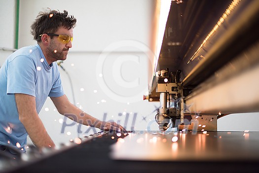 Within heavy industry. A man works in a modern factory on a CNC machine. Selective focus. High-quality photo
