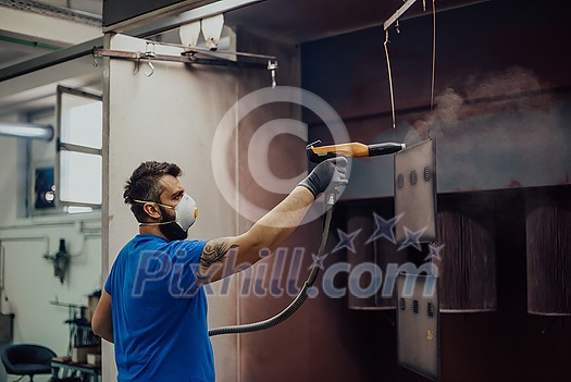 The painter paints the iron element. Industrial painting parts. Metal designs. High-quality photo