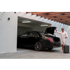 A senior man in a garage with glasses and modern casual clothes takes out his suitcases from the car. Selective focus. High-quality photo