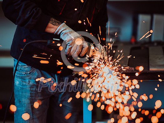 Heavy Industry Engineering Factory Interior with Industrial Worker Using Angle Grinder and Cutting a Metal Tube. Contractor in Safety Uniform and Hard Hat Manufacturing Metal Structures. High-quality photo