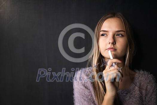 Pretty, young female student in front of a blackboard during class