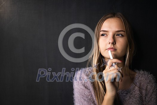 Pretty, young female student in front of a blackboard during class Pretty, young female student in front of a blackboard during class