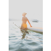 SUP Stand up paddle board concept - Pretty, young woman paddle boarding on a lovely lake in warm late afternoon light