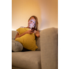 Cute young woman on a comfortable sofa in her modern apartment using her cell phone - staring at the blue lkight emitting device instaed of getting a good night sleep