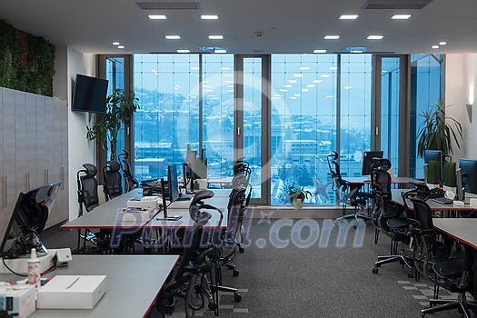 Front view of coworking office interior with workplaces, blank picture frame on wall and computer. . High quality photo