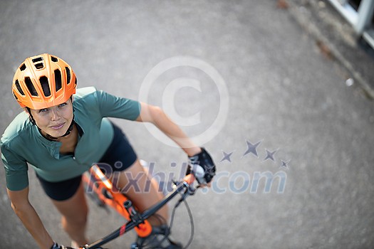 Pretty, young woman with her mountain bike going for a ride past the city limits, getting the daily cardio dose