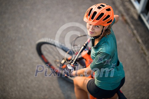 Pretty, young woman with her mountain bike going for a ride past the city limits, getting the daily cardio dose Pretty, young woman with her mountain bike going for a ride past the city limits, getting the daily cardio dose