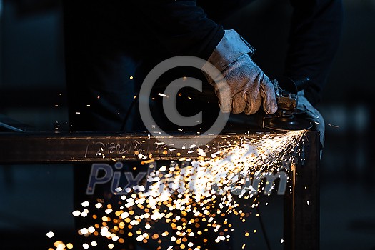 Man working on iron with grinder. Man at work. Sparkles and fire from grinder cutting. Grinder. Worker.