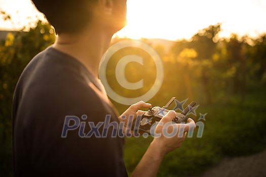 Young man flying a drone in warm evening sunlight Young man flying a drone in warm evening sunlight