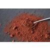 From above of teaspoon placed on heap of bitter cocoa powder of dark brown color on gray background