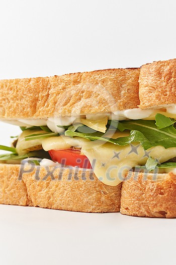 Closeup of delicious melted yellow cheese and arugula leaves between crunchy white bread toasted slices with golden crust placed on white background Closeup of delicious melted yellow cheese and arugula leaves between crunchy white bread toasted slices with golden crust placed on white background