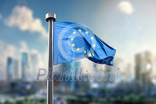 Flag of European Union against of the modern city on the background. Blurred cityscpae with skysrappers under blue sky and clouds