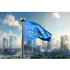 Flag of European Union against of the modern city on the background. Blurred cityscpae with skysrappers under blue sky and clouds