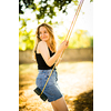 Carefree woman enjoying summer. Young woman is swinging on a swing in summer park garden.