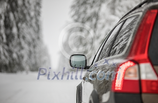 Car on a snowy winter road amid forests - using its four wheel drive capacities to get through the snow