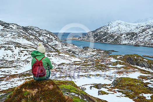 Woman tourist traveler enjoying a view of fjord in winter. Lofoten islands, Norway Woman tourist traveler enjoying a view of fjord in winter. Lofoten islands, Norway