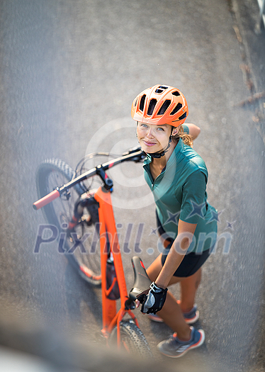 Pretty, young woman with her mountain bike going for a ride past the city limits, getting the daily cardio dose Pretty, young woman with her mountain bike going for a ride past the city limits, getting the daily cardio dose