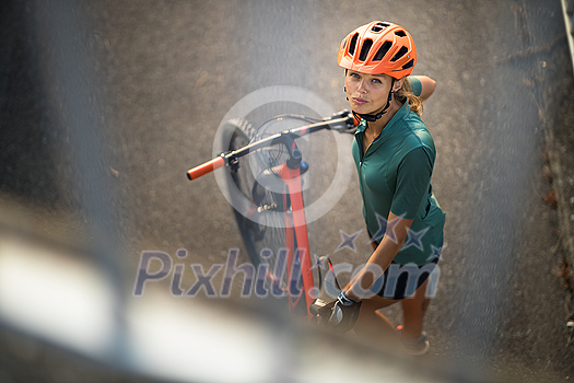 Pretty, young woman with her mountain bike going for a ride past the city limits, getting the daily cardio dose Pretty, young woman with her mountain bike going for a ride past the city limits, getting the daily cardio dose