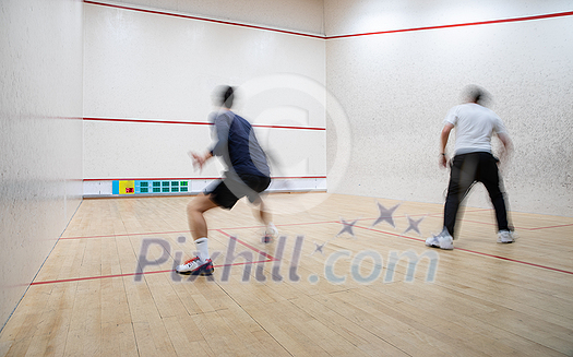 Squash players in action on a squash court (motion blurred image; color toned image)