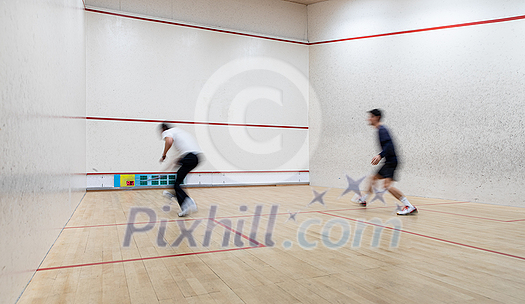 Squash players in action on a squash court (motion blurred image; color toned image) Squash players in action on a squash court (motion blurred image; color toned image)