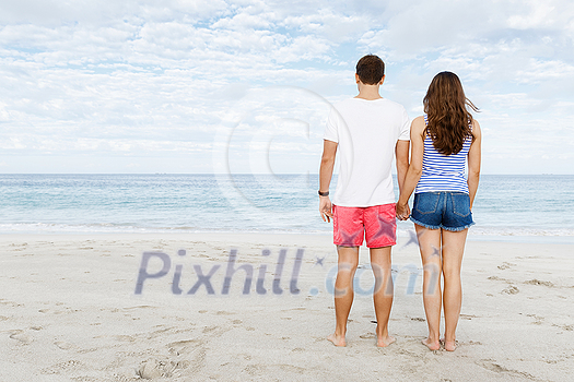 Young couple in love on the beach holding hands Young couple in love on the beach holding hands