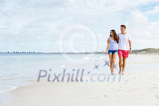 Romantic young couple on the beach waloking along the shore