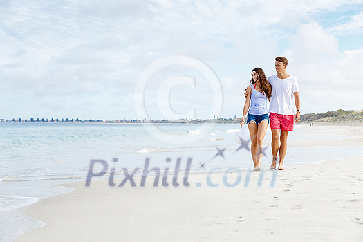 Romantic young couple on the beach waloking along the shore Romantic young couple on the beach waloking along the shore