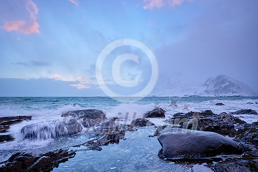 Beach of Norwegian sea on rocky coast in fjord on sunset in winter. Vareid beach, Lofoten islands, Norway