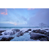 Beach of Norwegian sea on rocky coast in fjord on sunset in winter. Vareid beach, Lofoten islands, Norway