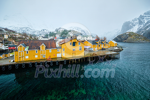 Panorama of Nusfjord authentic fishing village with yellow rorbu houses in Norwegian fjord in winter. Lofoten islands, Norway