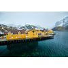 Panorama of Nusfjord authentic fishing village with yellow rorbu houses in Norwegian fjord in winter. Lofoten islands, Norway