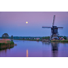 Netherlands rural lanscape with windmills at famous tourist site Kinderdijk in Holland in twilight with full moon