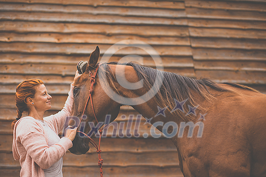 Pretty, young, redhead woman with her lovely horse, during her favorite leisure