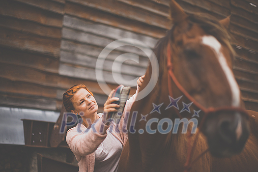 Pretty, young, redhead woman with her lovely horse, during her favorite leisure