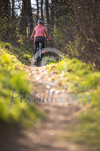 Pretty, young woman with her mountain bike going for a ride past the city limits, getting the daily dose of cardio