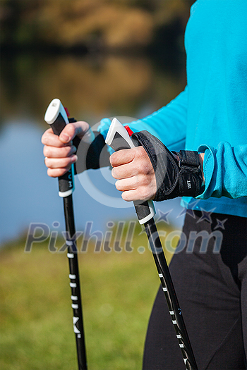 Nordic walking exercise adventure hiking concept - closeup of woman's hand holding nordic walking poles